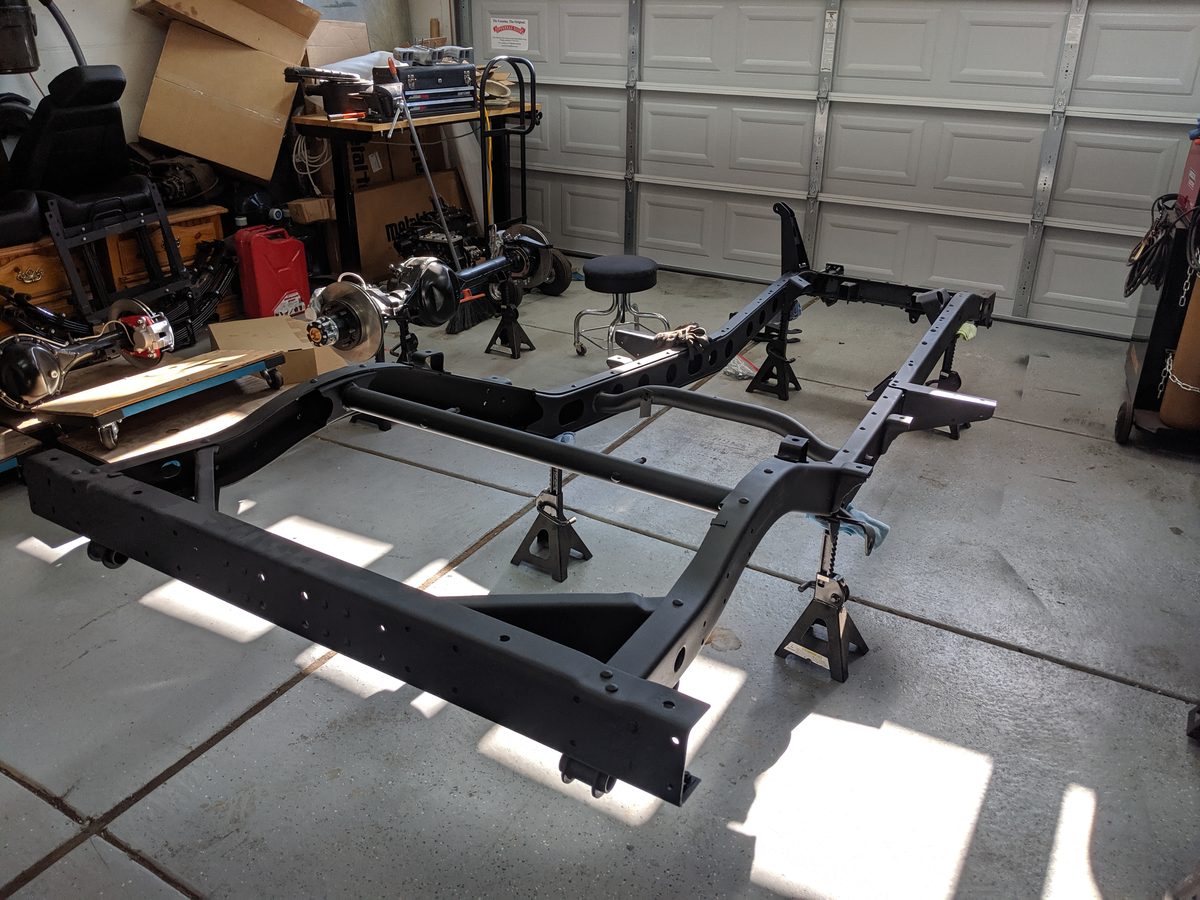 Clean powder-coated frame on jack stands with rebuilt axles staged